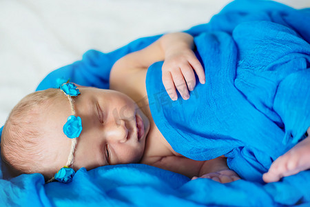 新生婴儿睡在蓝色背景上。