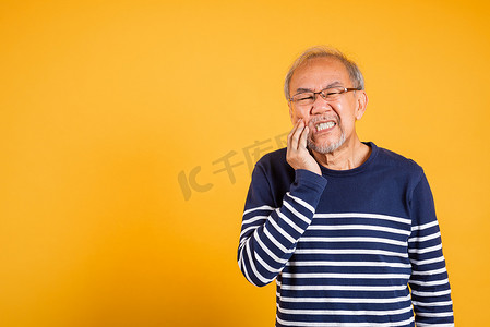 画像老年老人悲伤的手抚摸牙痛的脸颊