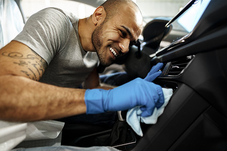 汽车内饰清洗摄影照片_清洁汽车内饰的男子，洗车服务中的汽车细节