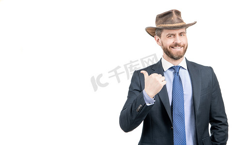 穿西装的老板摄影照片_戴着牛仔帽、身穿西装的快乐商人微笑着指着广告手势，做广告