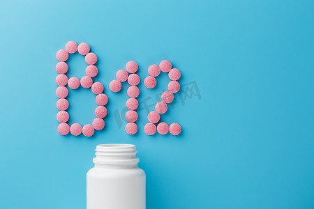 蓝色背景中粉红色圆形维生素 B12 形药丸从白色罐头中溢出