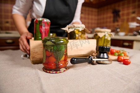 重点关注放在接缝钥匙附近的桌子上的一罐腌制樱桃番茄和一盒罐装蔬菜。