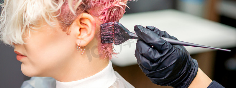 染头摄影照片_理发师将头发染成粉红色