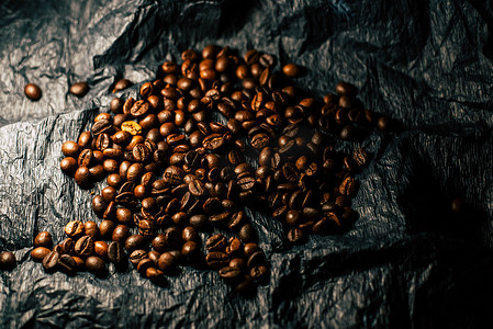 黑色杯子上摄影照片_黑色背景上的咖啡豆