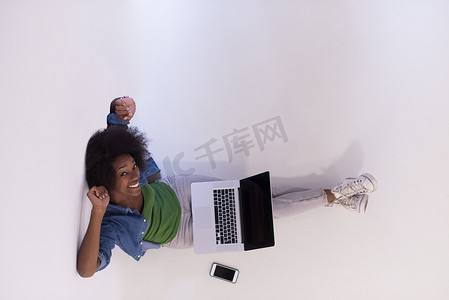 笔记本电脑俯视摄影照片_非洲裔美国女性坐在地板上，笔记本电脑俯视