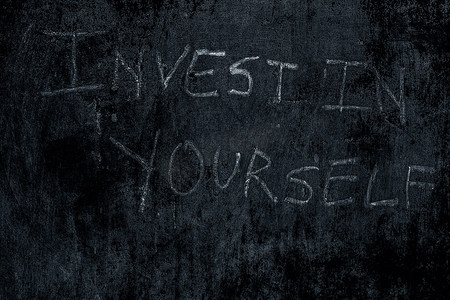 “投资你自己”写在粗糙的墙上，水平拍摄。