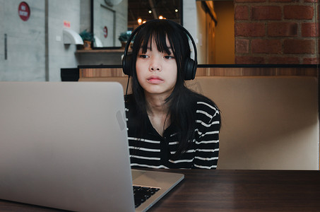 女孩使用笔记本电脑看电影或用耳机和数字互联网通信社交网络听音乐。