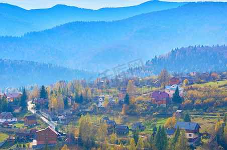 蓝色薄雾中山谷和山脉中秋季小村庄的鸟瞰图