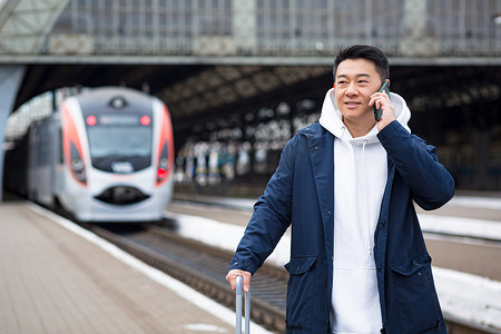 地铁玩手机摄影照片_火车站的亚洲商人在电话里玩得很开心