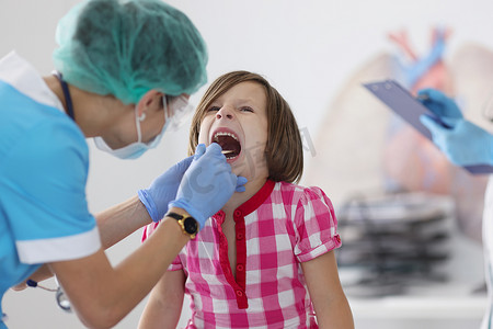 小孩张嘴检查，喉咙痛，儿科医生用工具预约检查