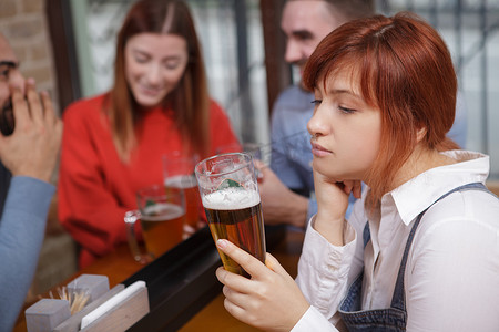 悲伤的女人在酒吧喝啤酒