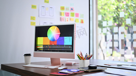 设计工作室的显示器屏幕、咖啡杯和文具上带有彩色图表的现代电脑 pc。