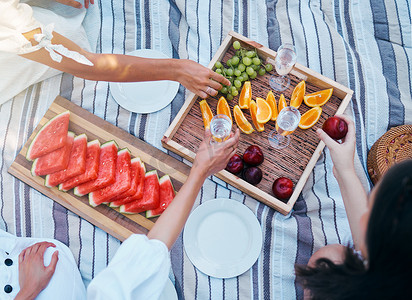 夏天，朋友们的手、野餐和水果，在公园里吃着葡萄酒，喝着奢华、营养和葡萄庆祝香槟。