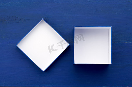打开空方形纸板盒，在蓝色木质背景上放礼物