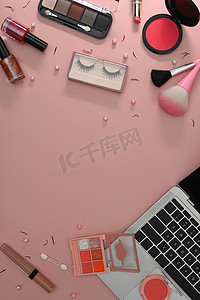 粉红色背景的顶视图笔记本电脑、化妆刷和化妆品。