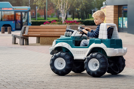 人骑电动车摄影照片_有趣的男孩骑着一辆玩具电动车。