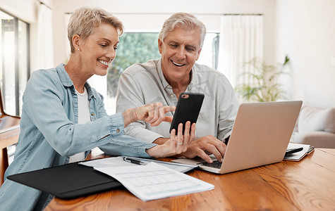 省吃俭用摄影照片_电话、笔记本电脑和财务，一对年长的夫妇在家里处理遗嘱、储蓄或投资文件。