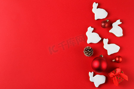 2023喜庆摄影照片_兔子形状的美味姜饼和红色背景的圣诞装饰。