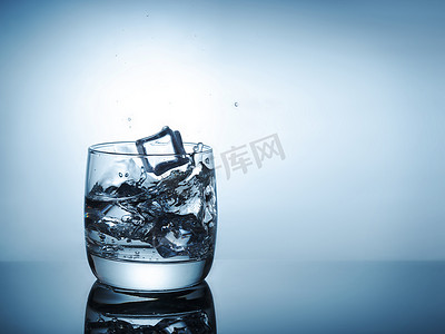 冰块杯水摄影照片_飞溅入杯水的冰块