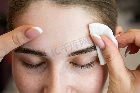 师傅先用化妆棉为白人女性处理眉毛，然后再层压眉毛。