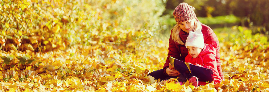 妈妈在秋天的公园教女儿，妈妈教女儿读书。