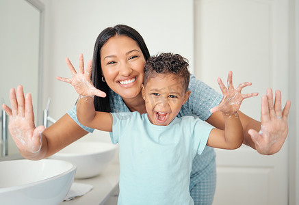 水里的手摄影照片_母亲和儿子在浴室里双手干净，手掌张开，手掌被清洁并覆盖着泡沫，教孩子洗手。