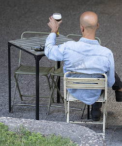 在马德里市中心的桌子上享用一杯啤酒的男子的后视图