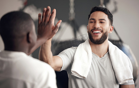 一位自信的年轻西班牙裔男子在健身房锻炼时向他的朋友高举五分。