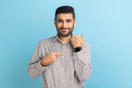留着胡子的积极商人指着手边的手表，微笑着展示新的智能时钟。