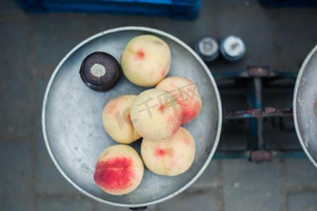 老式秤摄影照片_市场上老式秤上的甜熟桃子