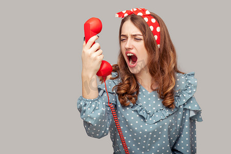 新年促销宣传海报摄影照片_恼怒的海报女孩对着手机大喊大叫，大喊大叫，因电话交谈而恼火，连接不良