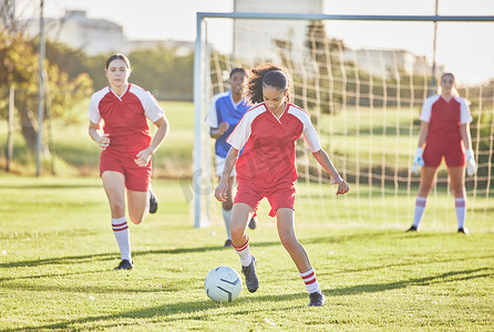 女子足球队、体育队和女子队在球场上踢球、铲球和带球奔跑。