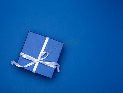 蓝色礼物摄影照片_蓝色方形盒子，上面有蓝色经典背景上带蝴蝶结的礼物