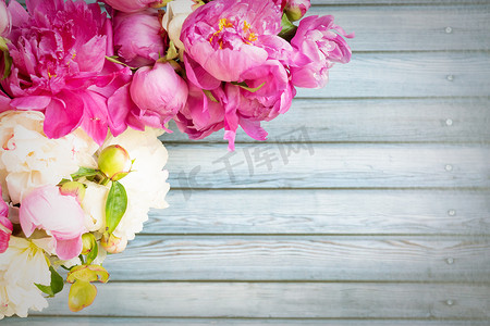 婚礼边框粉色摄影照片_木桌上美丽的粉色和白色牡丹花的边框，带有复制空间，供您的文字顶视图和平铺风格