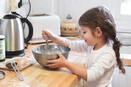 可爱的小女孩在厨房里用搅拌器和搅拌碗搅拌