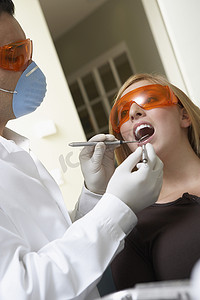 医用护理口罩摄影照片_牙医用他的设备检查女人的牙齿