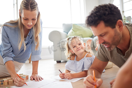 家庭绘画、创意微笑和女孩与父母一起在客厅地板上，在纸上写字，并在休息室里玩游戏感到高兴。