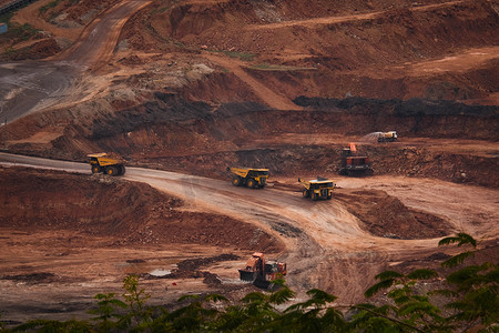 卡车和挖掘机在褐煤矿露天矿坑中工作的视图。