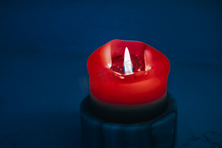 蓝色和红色火焰摄影照片_蓝色背景的红色节日蜡烛、圣诞节、除夕和情人节的奢侈品牌设计和装饰