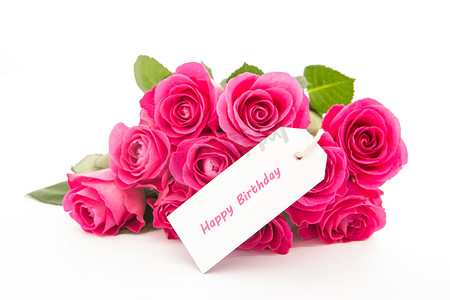 生日快乐背景粉色摄影照片_一束美丽的粉红玫瑰的特写，白色背景上有一张生日快乐卡