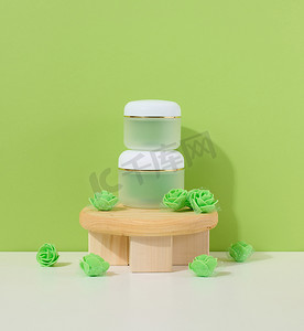 包装设计样机摄影照片_白色桌子上的化妆品绿色罐子。