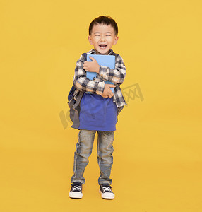 黄色背景中快乐的亚洲孩子拿着或拥抱大书