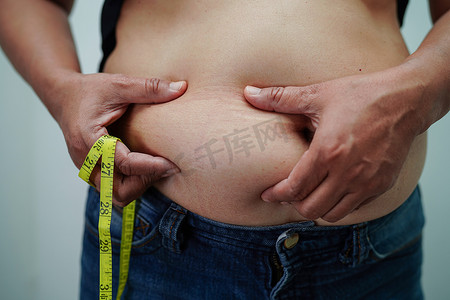 饮食健身摄影照片_超重的亚洲女性用手挤压脂肪腹部大尺寸超重和肥胖。