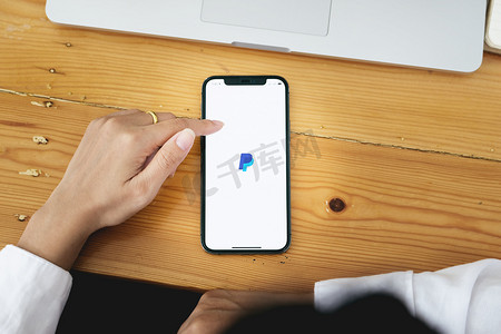 泰国清迈 - 2021 年 5 月 30 日：女性手拿着 iphone，屏幕上有 PayPal 应用程序。 
