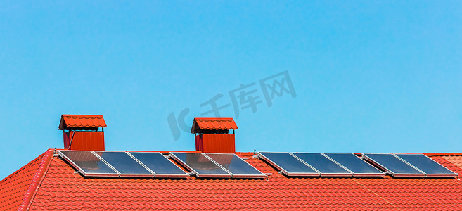 蓝光天空下建筑物或房屋红瓦屋顶上的太阳能电池板