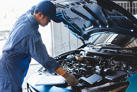 汽车修理工通过剪贴板中的列表在汽车修理店车库中按客户索赔订单检查维修车辆。