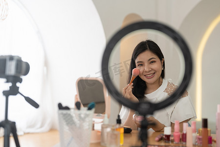 亚洲年轻女性博主在家中用化妆化妆品录制视频博客视频，在线影响社交媒体概念。直播病毒