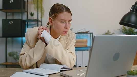 学习规划摄影照片_身着西装的女商人律师在网上使用笔记本电脑工作，在办公室的规划笔记本上写笔记