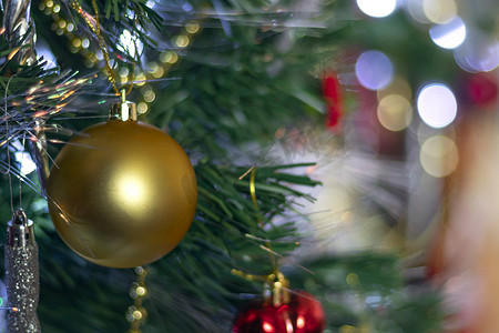 新年或圣诞节背景上的大金色圣诞球，配有绿树、白色雪花、彩色玩具和带散景和复制空间的金珠。