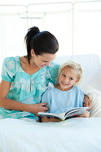女孩在医院病床上和母亲一起读书